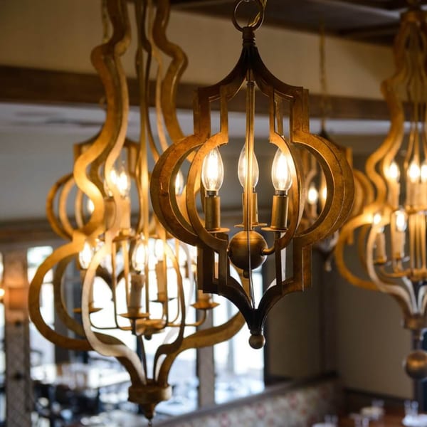 Ornate golden chandeliers with glowing bulbs illuminate the Krinti Mediterranean Grill dining area.