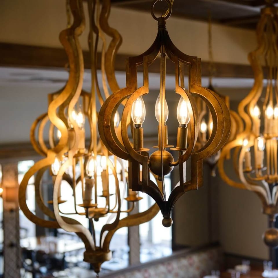 Ornate golden chandeliers with glowing bulbs illuminate the Krinti Mediterranean Grill dining area.