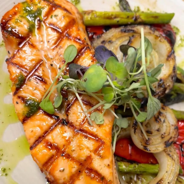 Grilled salmon with pesto, microgreens, asparagus, and charred onions from Krinti Mediterranean Grill.